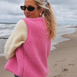 Frau trägt die pinke TYB Wollweste am Strand
